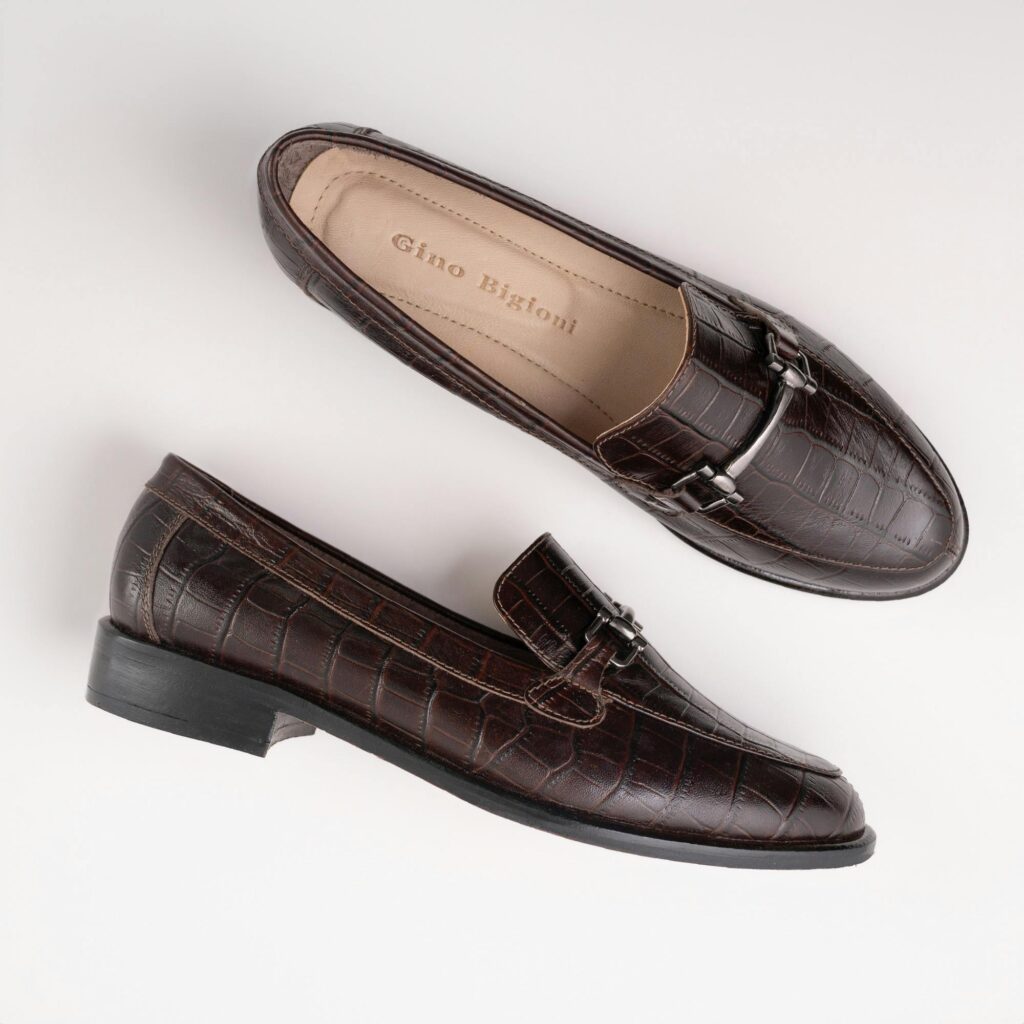 Sapato estilo loafer de couro marrom com detalhe em fivela metálica, visual estruturado.