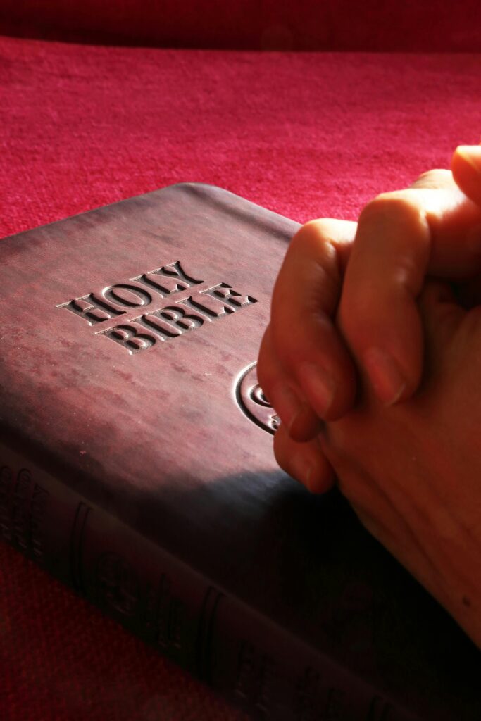 Mãos femininas sobre um livro sagrado, simbolizando a busca por conhecimento espiritual.