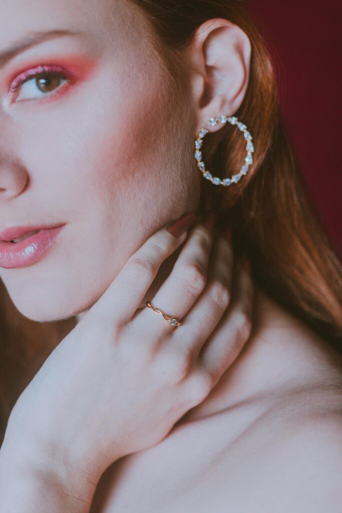 Close-up de orelha feminina usando argola cravejada com brilhantes, destacando o luxo da peça.