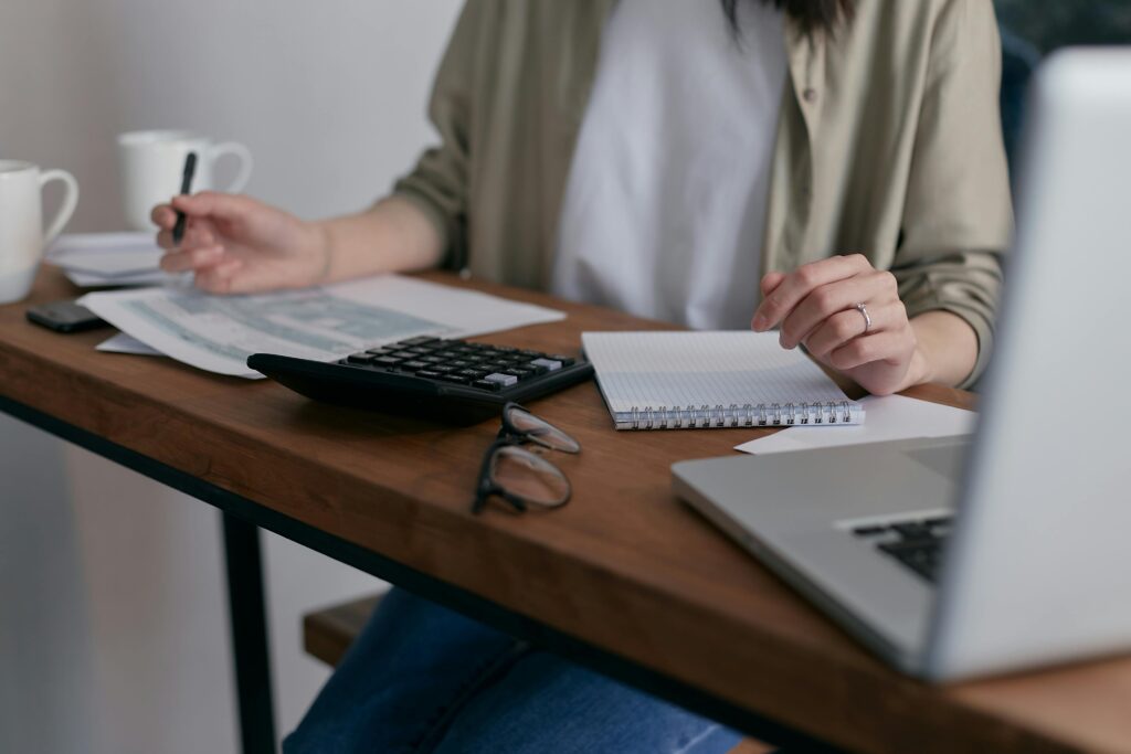 Visão de uma mulher controlando despesas em uma planilha. A imagem representa o processo de quitação de dívidas e a retomada do controle financeiro pessoal.
