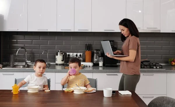 Mãe organizando uma rotina de cuidados em uma bancada prática na cozinha, com itens do bebê e agenda, ilustrando a adaptação do lar e do tempo após o nascimento.