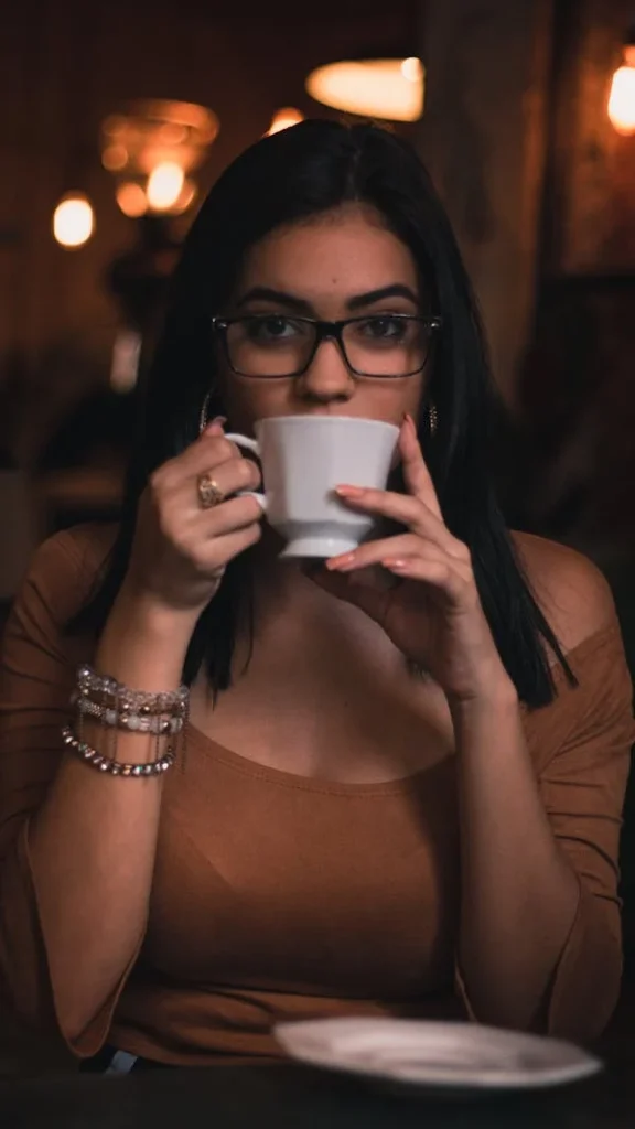Uma mulher segurando uma xícara de café fumegante, em um ambiente aconchegante, simbolizando o bem-estar e os benefícios da bebida para a rotina feminina.