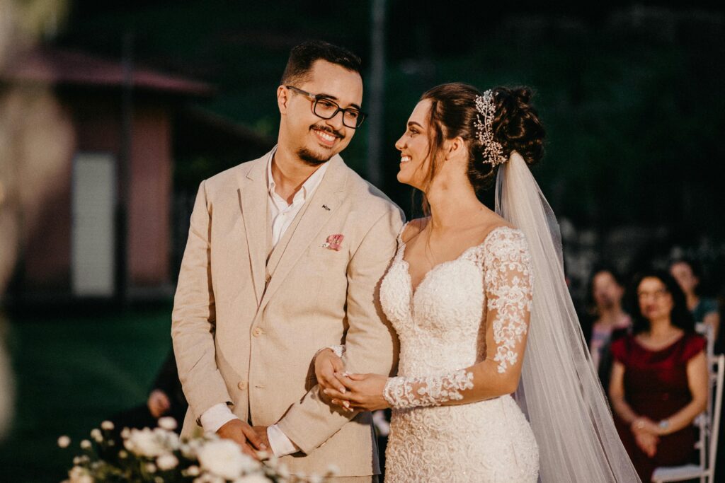 Noivos no altar decorado com flores brancas, sob uma luz suave, capturando o momento solene e emocionante da cerimônia de casamento