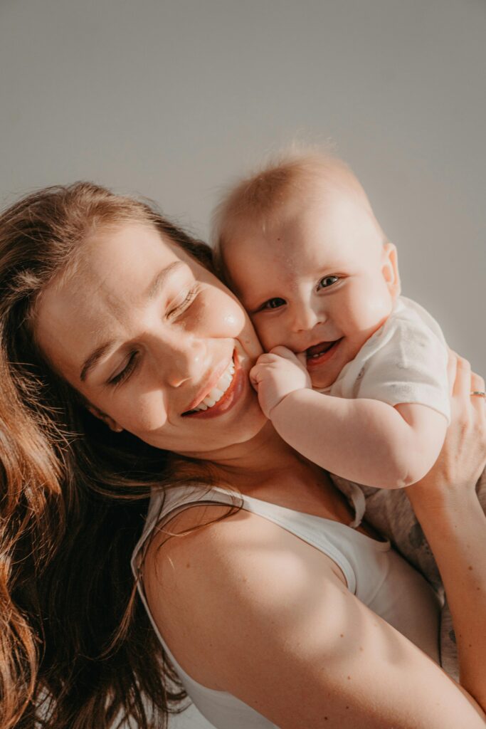Mulher sorridente abraçando carinhosamente uma criança, transmitindo afeto e cumplicidade, ilustrando o laço da maternidade por adoção.